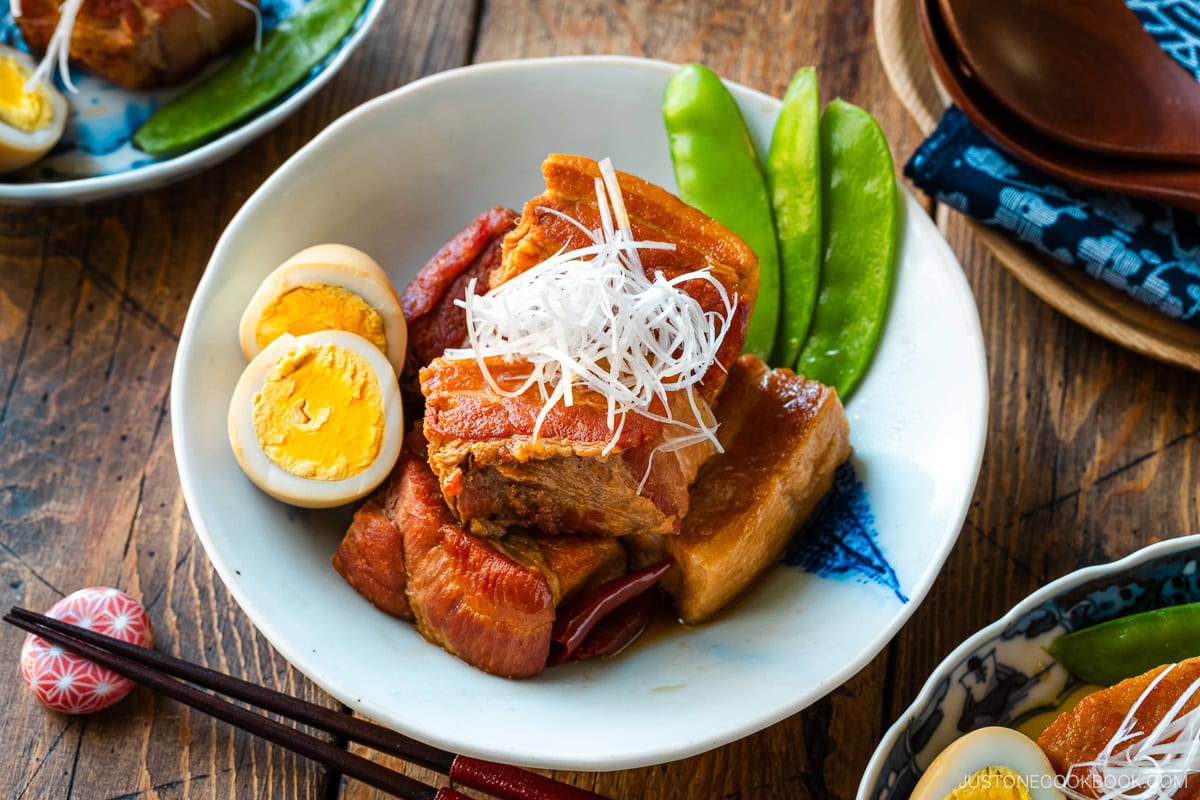 A bowl containing Kakuni, Japanese braised pork belly, served with julienned white scallion, boiled egg, and karashi mustard.