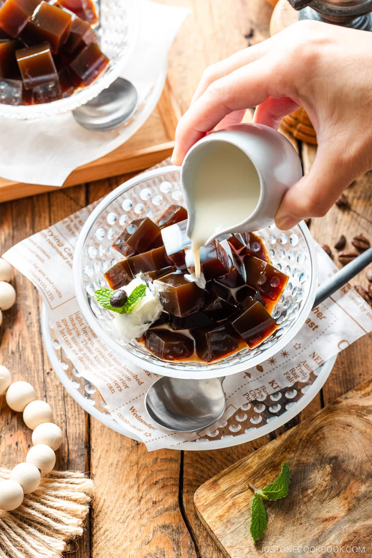 Glass bowls containing Coffee Jelly, drizzled with cream and topped with fresh whipped cream.