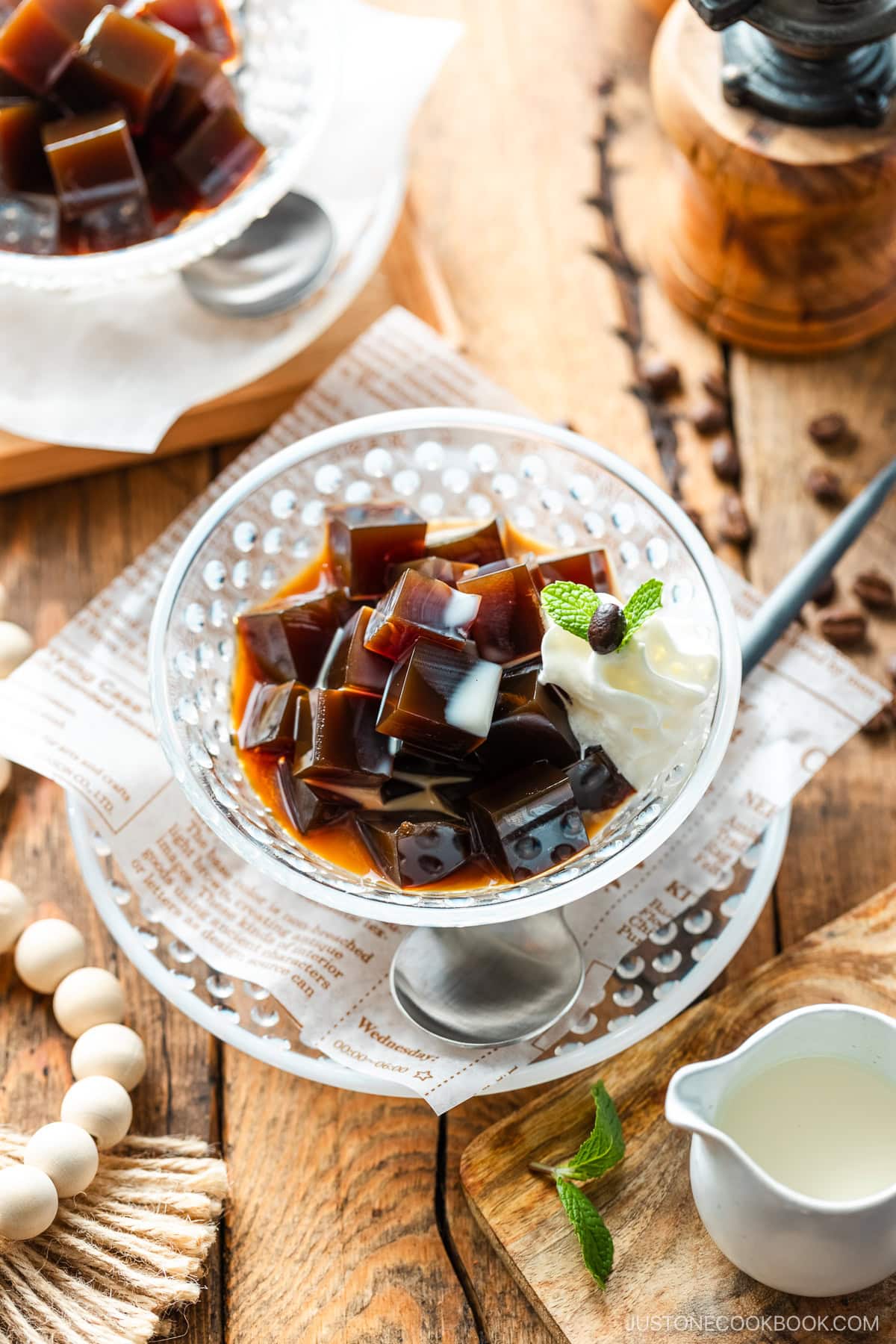 Glass bowls containing Coffee Jelly, drizzled with cream and topped with fresh whipped cream.