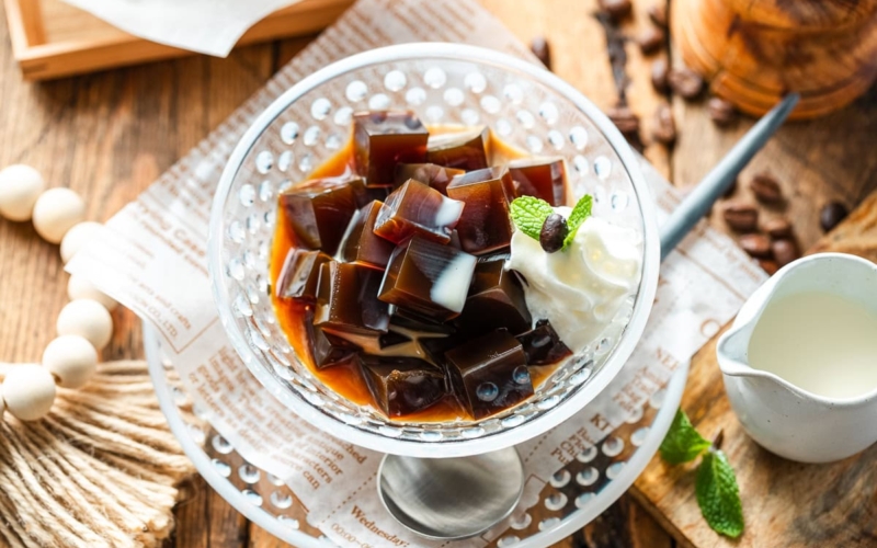 Glass bowls containing Coffee Jelly, drizzled with cream and topped with fresh whipped cream.