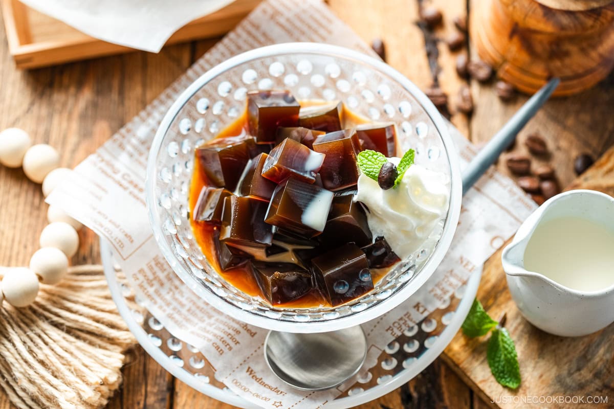 Glass bowls containing Coffee Jelly, drizzled with cream and topped with fresh whipped cream.