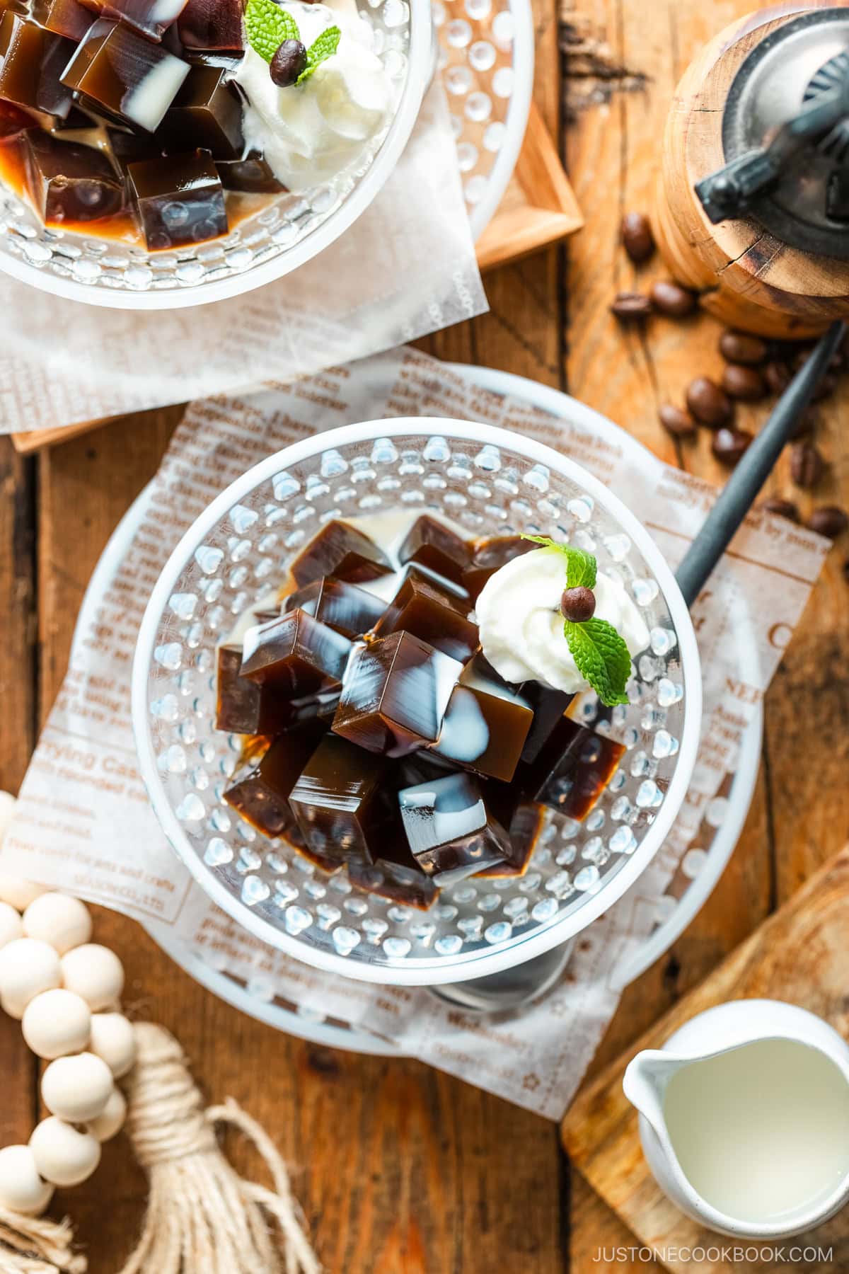 Glass bowls containing Coffee Jelly, drizzled with cream and topped with fresh whipped cream.