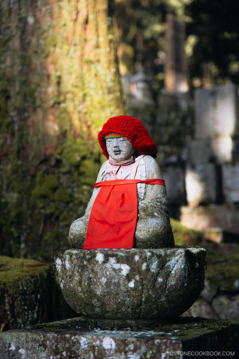 Stone buddha statue with red hat and bib