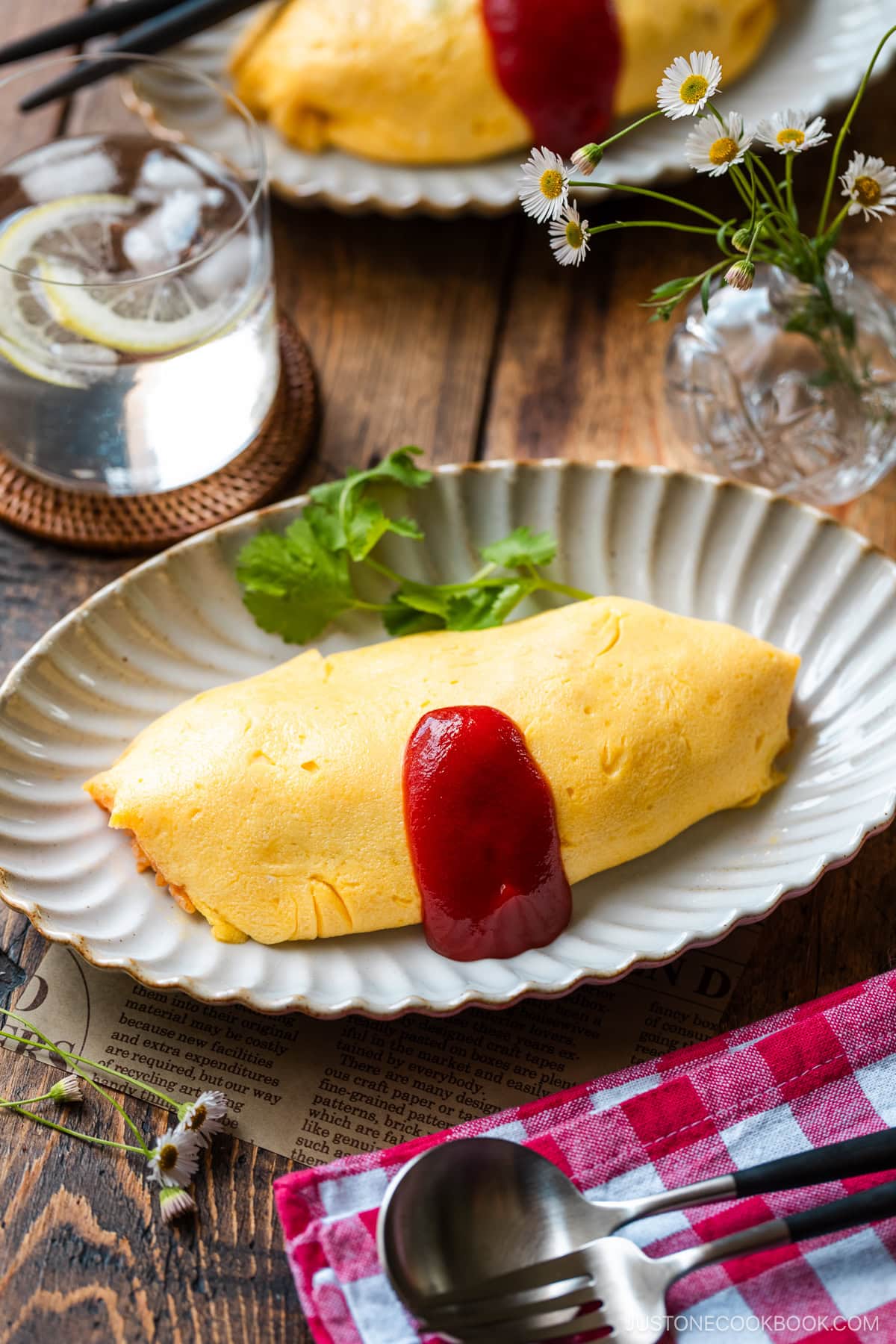 An oval plate containing Omurice (Japanese Omelette Rice) drizzled with Japanese ketchup.