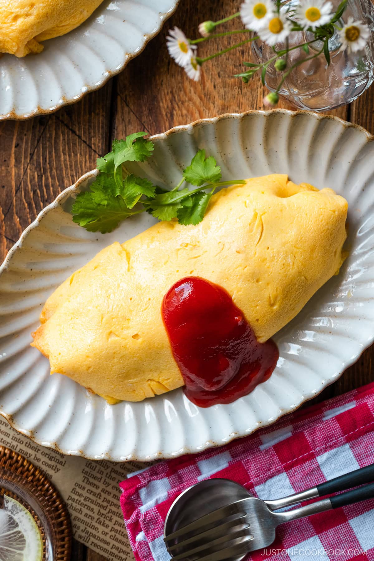 An oval plate containing Omurice (Japanese Omelette Rice) drizzled with Japanese ketchup.