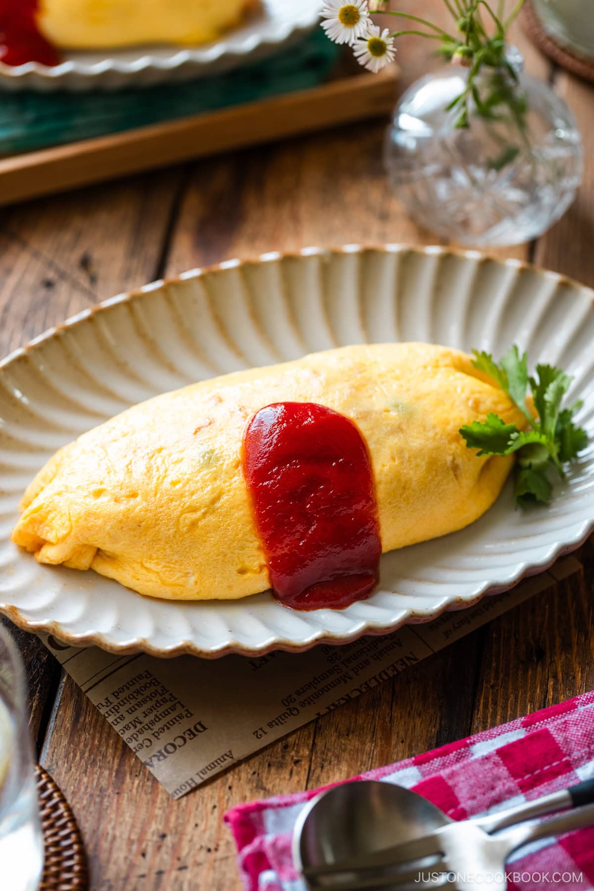 An oval plate containing Omurice (Japanese Omelette Rice) drizzled with Japanese ketchup.