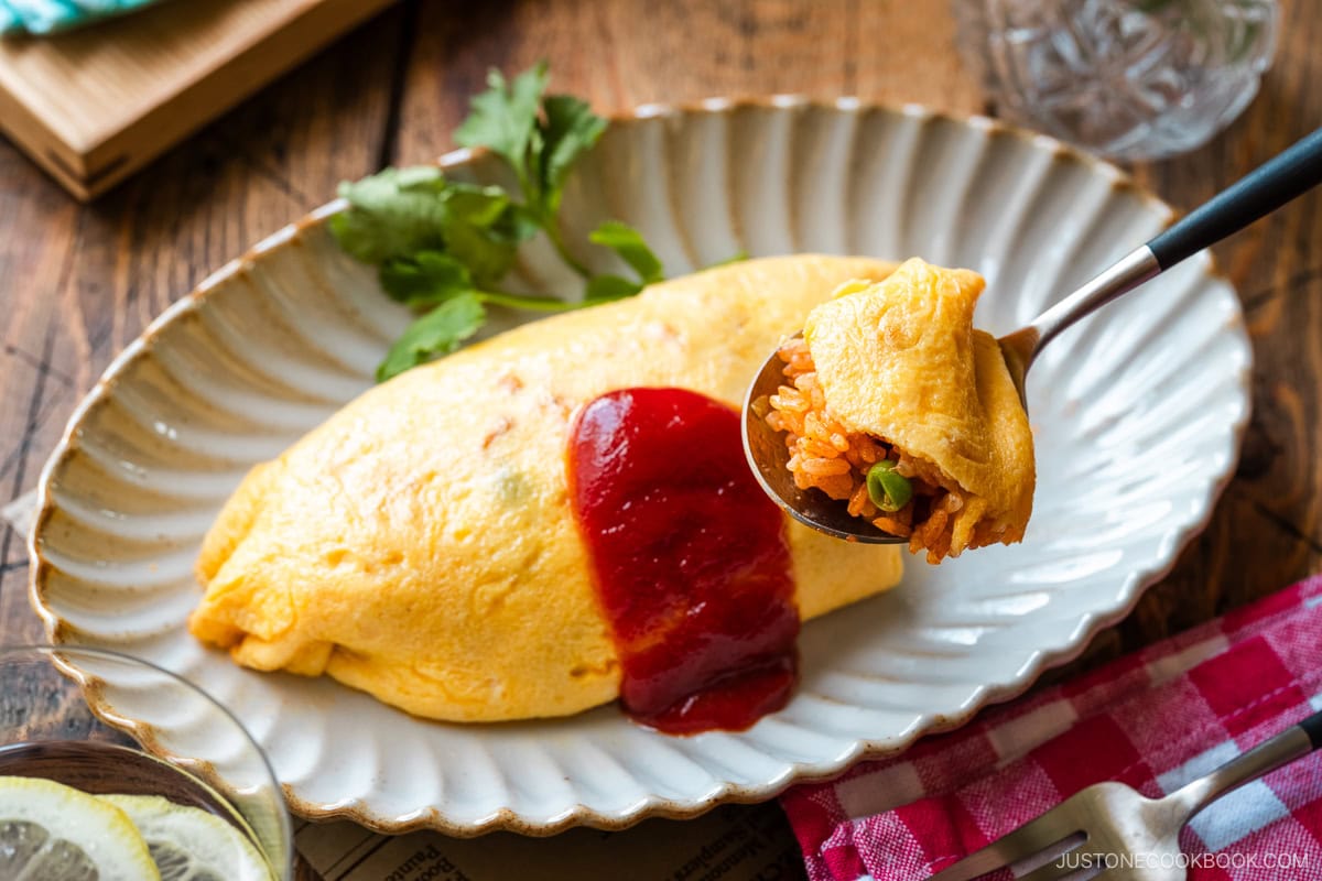 An oval plate containing Omurice (Japanese Omelette Rice) drizzled with Japanese ketchup.