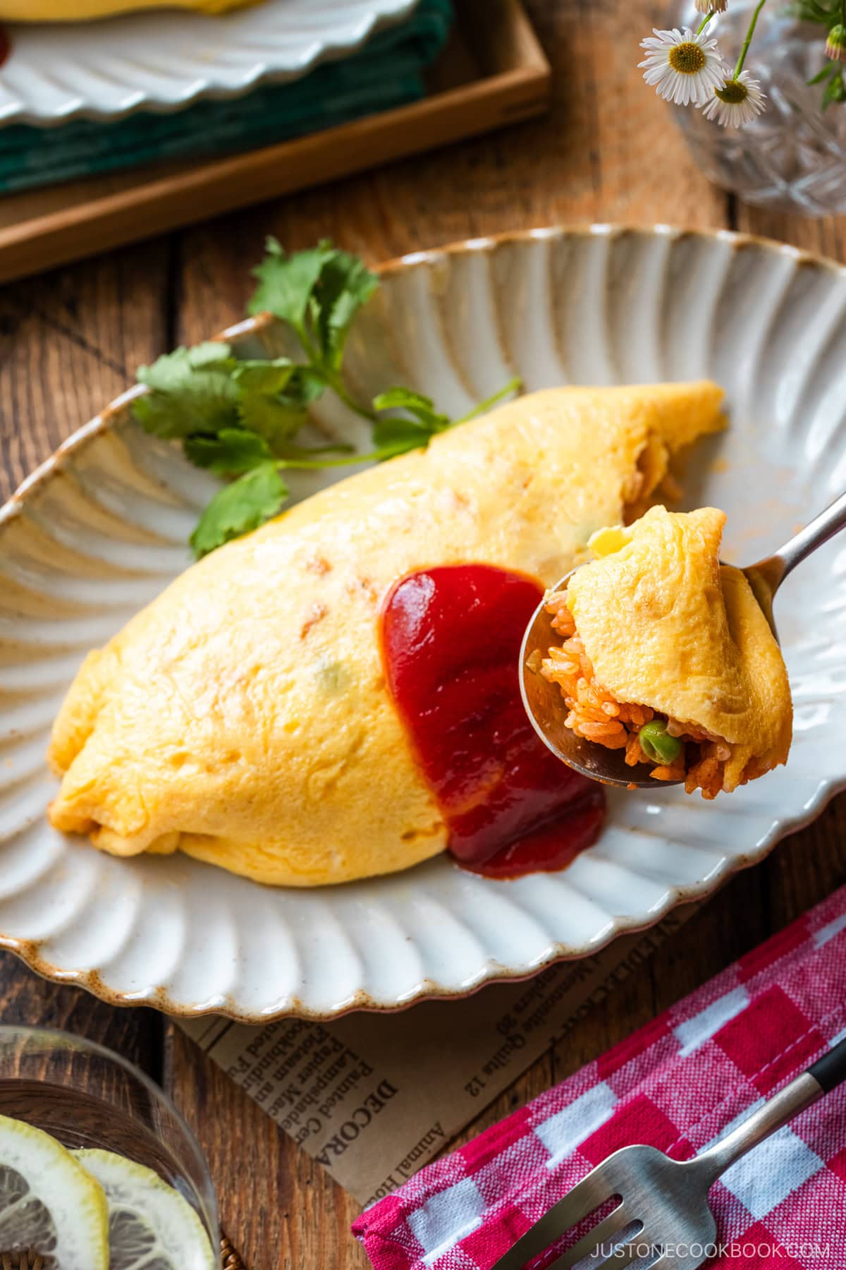 An oval plate containing Omurice (Japanese Omelette Rice) drizzled with Japanese ketchup.