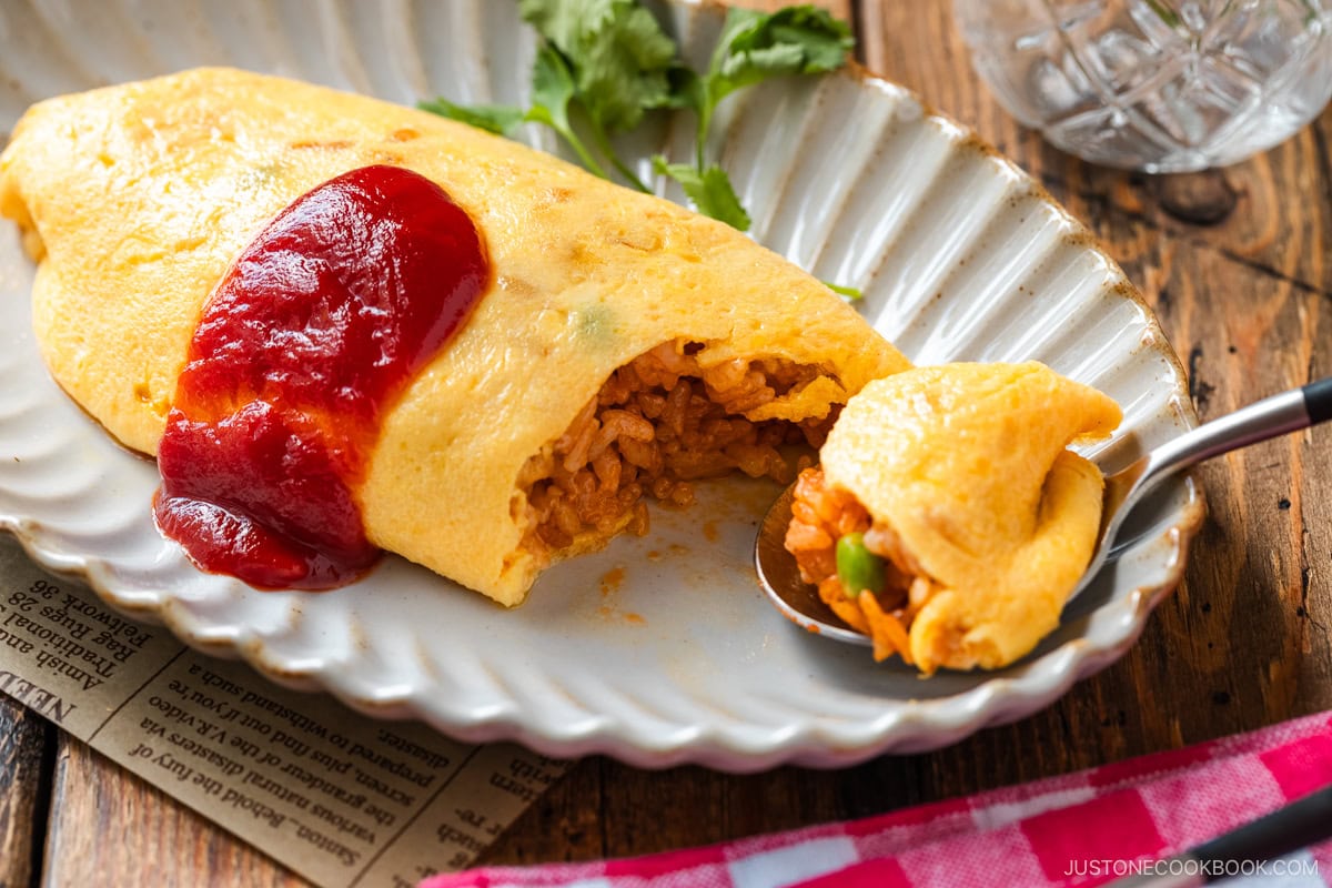 An oval plate containing Omurice (Japanese Omelette Rice) drizzled with Japanese ketchup.