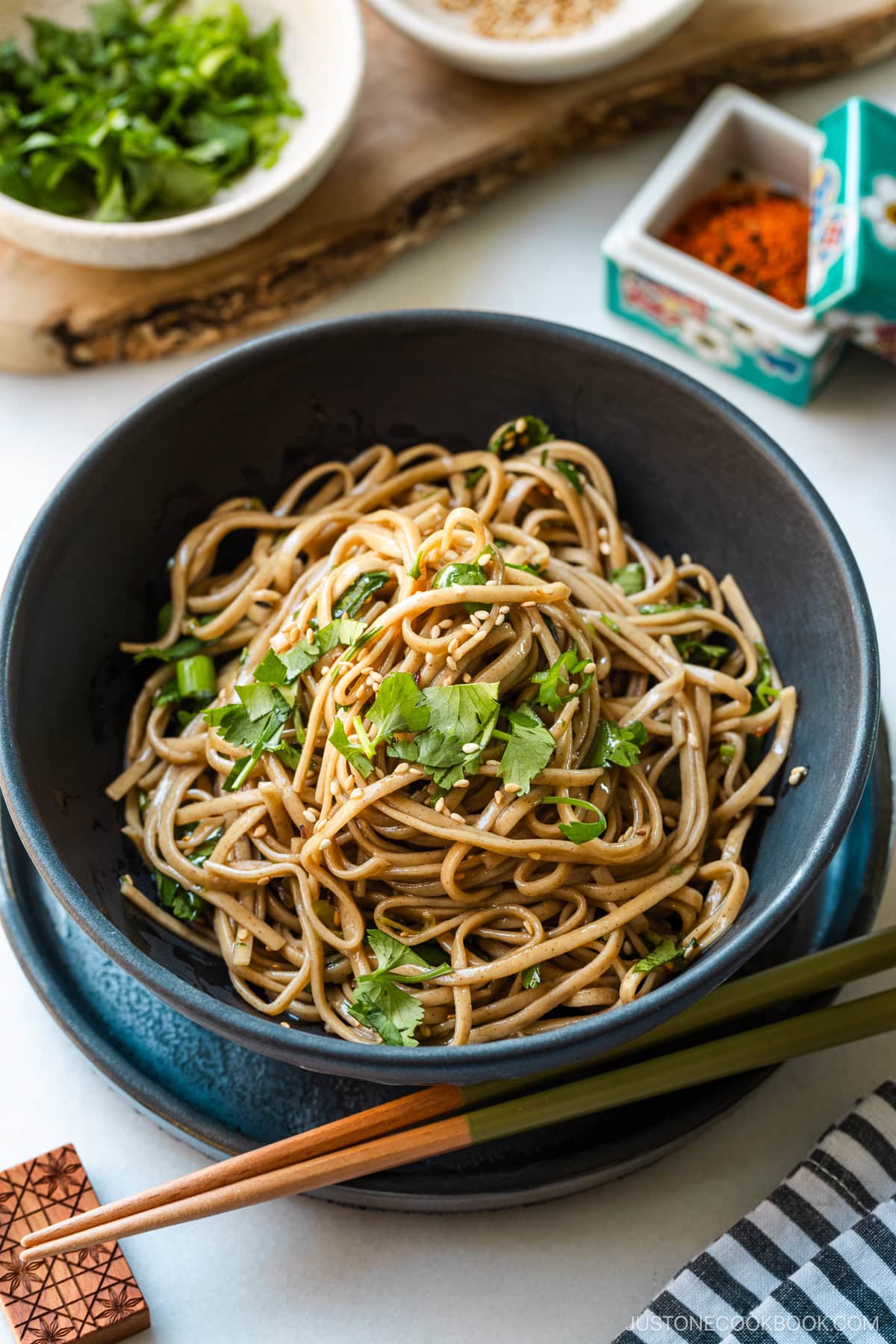 A black bowl containing Soba Noodle Salad topped with sesame seeds and chopped cilantro and green onions.