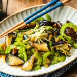 An oval fluted plate containing Stir-Fried Bitter Melon and Eggplant topped with julienned ginger.