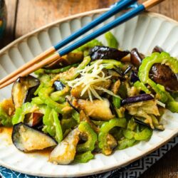 An oval fluted plate containing Stir-Fried Bitter Melon and Eggplant topped with julienned ginger.
