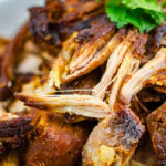 A white bowl containing Beer-Braised Carnitas.
