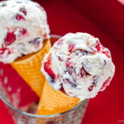 A glass cup containing cherry ice cream on a waffle cone.