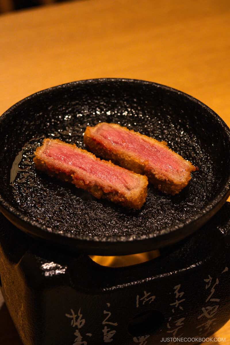 Two pieces of gyukatsu frying on hot plate