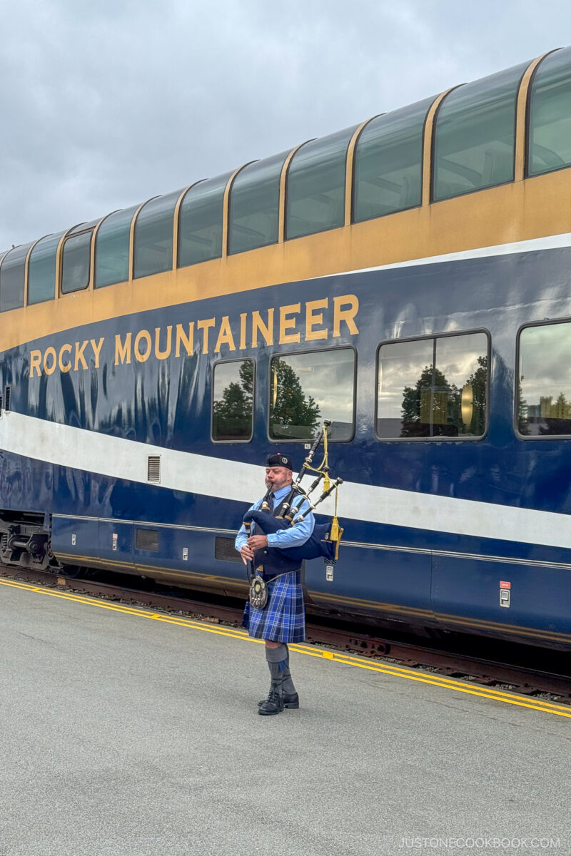 a person playing bagpipe in front of Rocky Mountaineer train