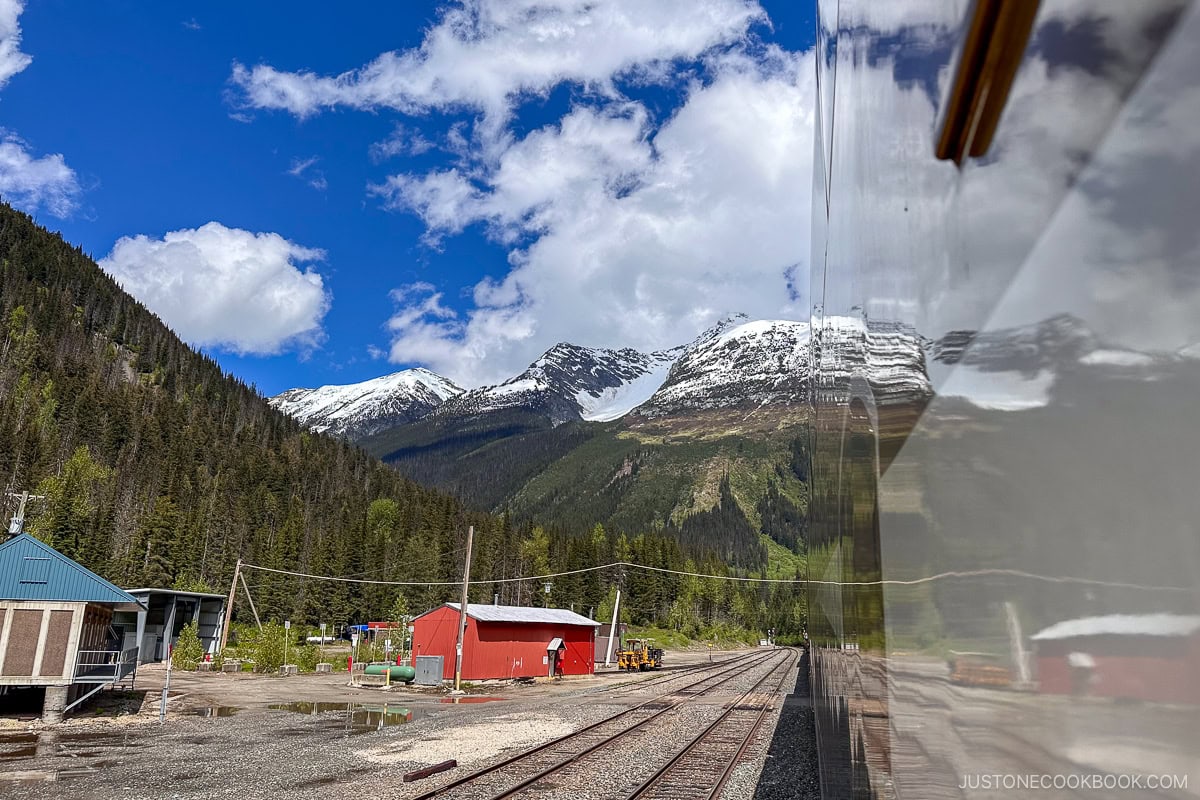Canadian Rockies reflect on a train next to train tracks