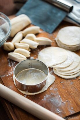 Homemade gyoza wrappers on a wooden cutting board.