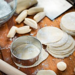 Homemade gyoza wrappers on a wooden cutting board.