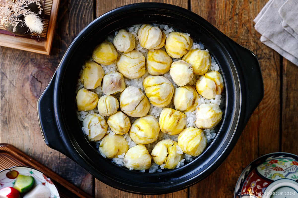 A ceramic donabe pot containing Japanese chestnut rice (kuri gohan); peeled chestnuts beautifully laying over steamed rice in a single layer.
