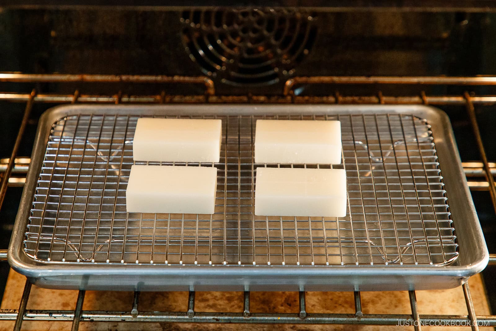 Kiri mochi on the wire rack over the baking sheet placed in the oven.