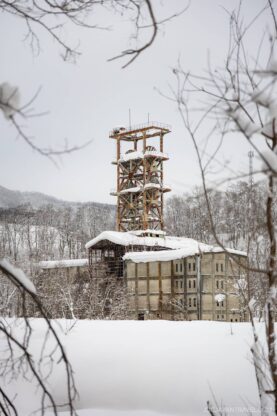 Old rusty coal mine tower covered in snow