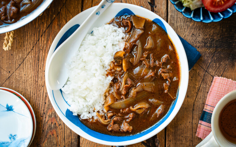 A round shallow bowl containing a bed of steamed rice and Hayashi Rice.