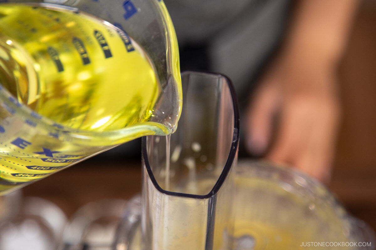 With the food processor running on the Stir setting, SLOWLY add about one-third of the neutral oil in a thin, steady stream. The mixture will begin to thicken and emulsify.