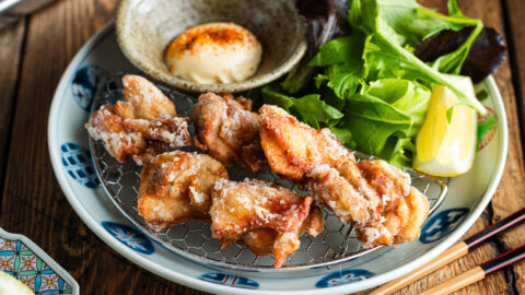 Beautiful Japanese plates containing karaage, Japanese fried chicken, garnished with lemon wedges and kewpie mayo dollop sprinkled with shichimi togarashi.