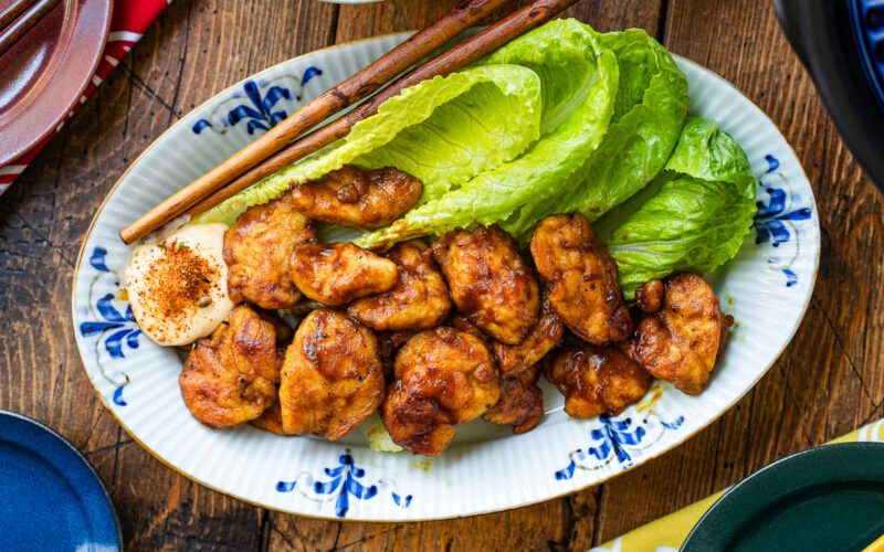 An oval shape plate containing Pan-Fried Curry Chicken garnished with lettuce.