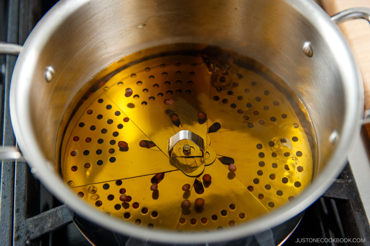 A stainless steel boiling azuki beans with a drop lid (otoshibuta) on top.