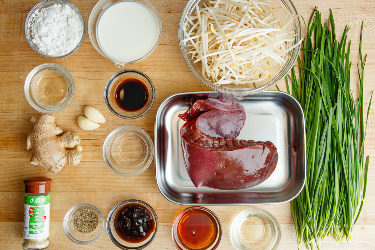  raw pork liver, fresh garlic chives, bean sprouts, ginger, garlic, various sauces, spices, cornstarch, milk, and small bowls with liquids.