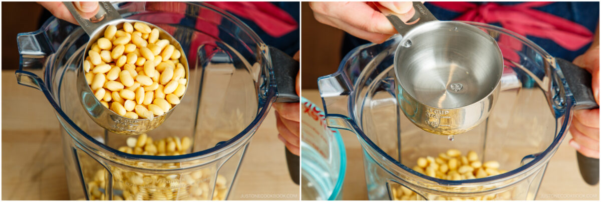 A person pours pine nuts and then water from a measuring cup into a blender, preparing ingredients for a recipe.