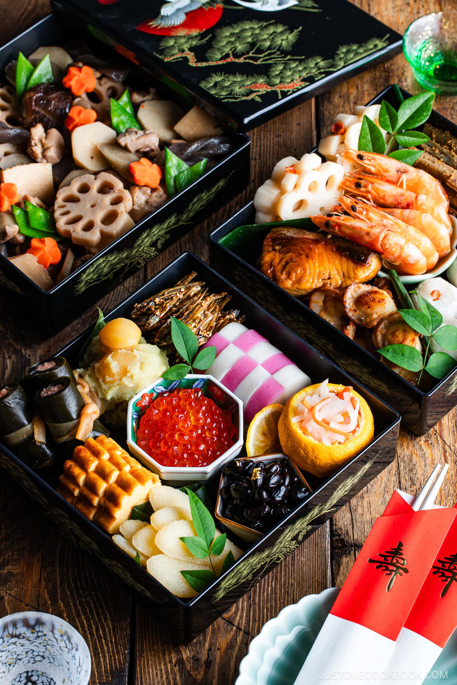 A beautifully arranged Japanese New Year’s bento box (osechi ryori) filled with assorted colorful traditional foods, including shrimp, fish, lotus root, rolled omelette, and various vegetables in lacquered black boxes.