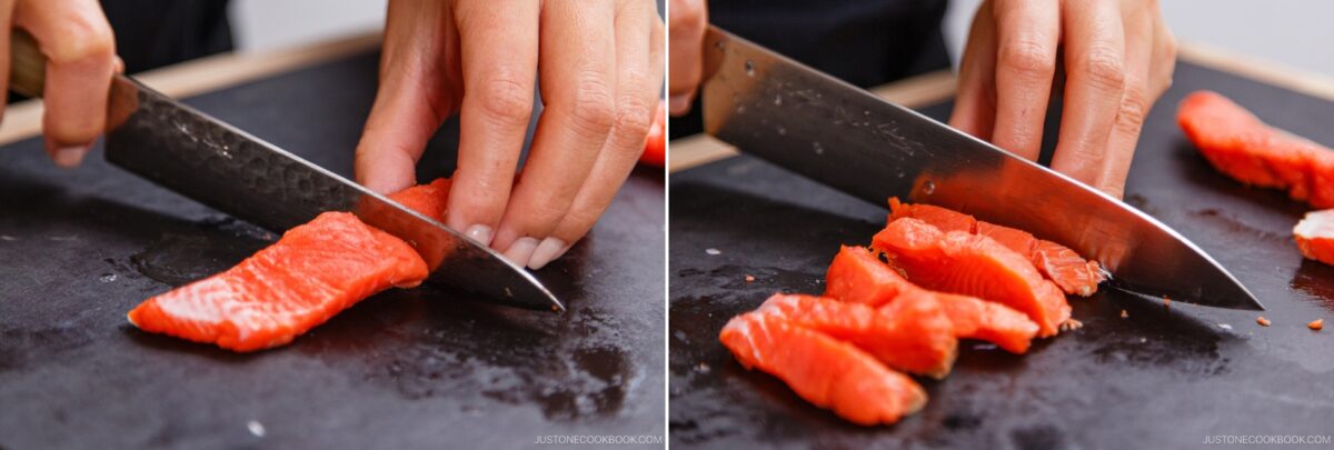 Close-up of hands slicing raw salmon with a sharp knife on a black cutting board, preparing thin slices for Kobumaki (Salmon Kombu Roll). The salmon pieces are being carefully cut for this delicate Japanese dish.