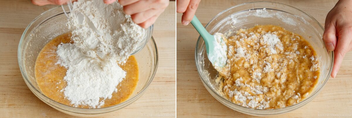 A person adds flour to a bowl of wet ingredients and then uses a spatula to mix the batter for Brown Butter Banana Bread, likely preparing dough or cake batter on a wooden surface.