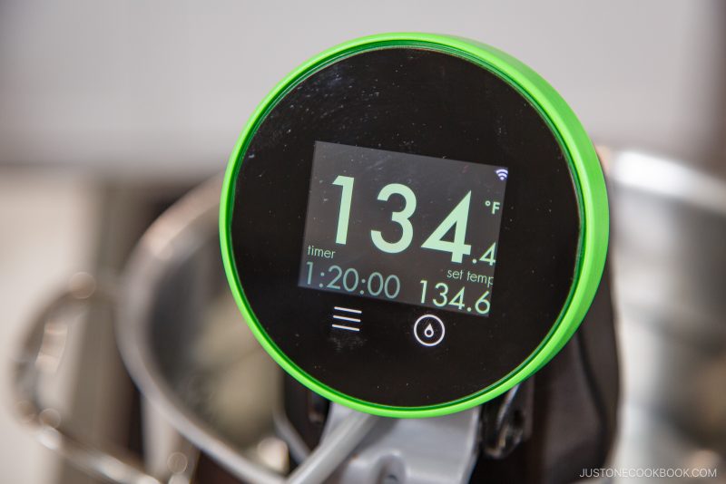 A close-up of a digital sous vide cooker display showing a temperature of 134°F, a set temperature of 134.6°F, and a timer set for 1 hour and 20 minutes—a perfect setup for learning how to pasteurize eggs at home. The device has a green rim.